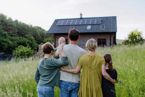 Familie auf Wiese vor einem Haus 