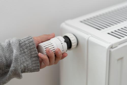 Hand dreht Thermostat einer Heizung.