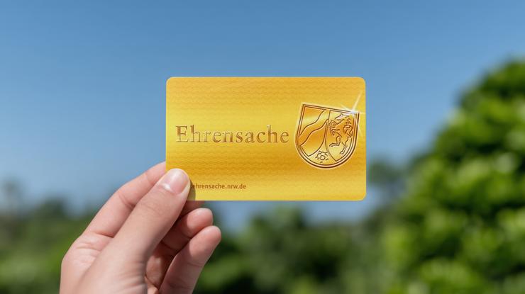 Hand hält Ehrenamtskarte in die Luft.